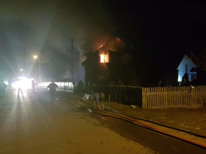 Policjanci wspólnie ze strażakami wynoszą mienie z płonącego domu